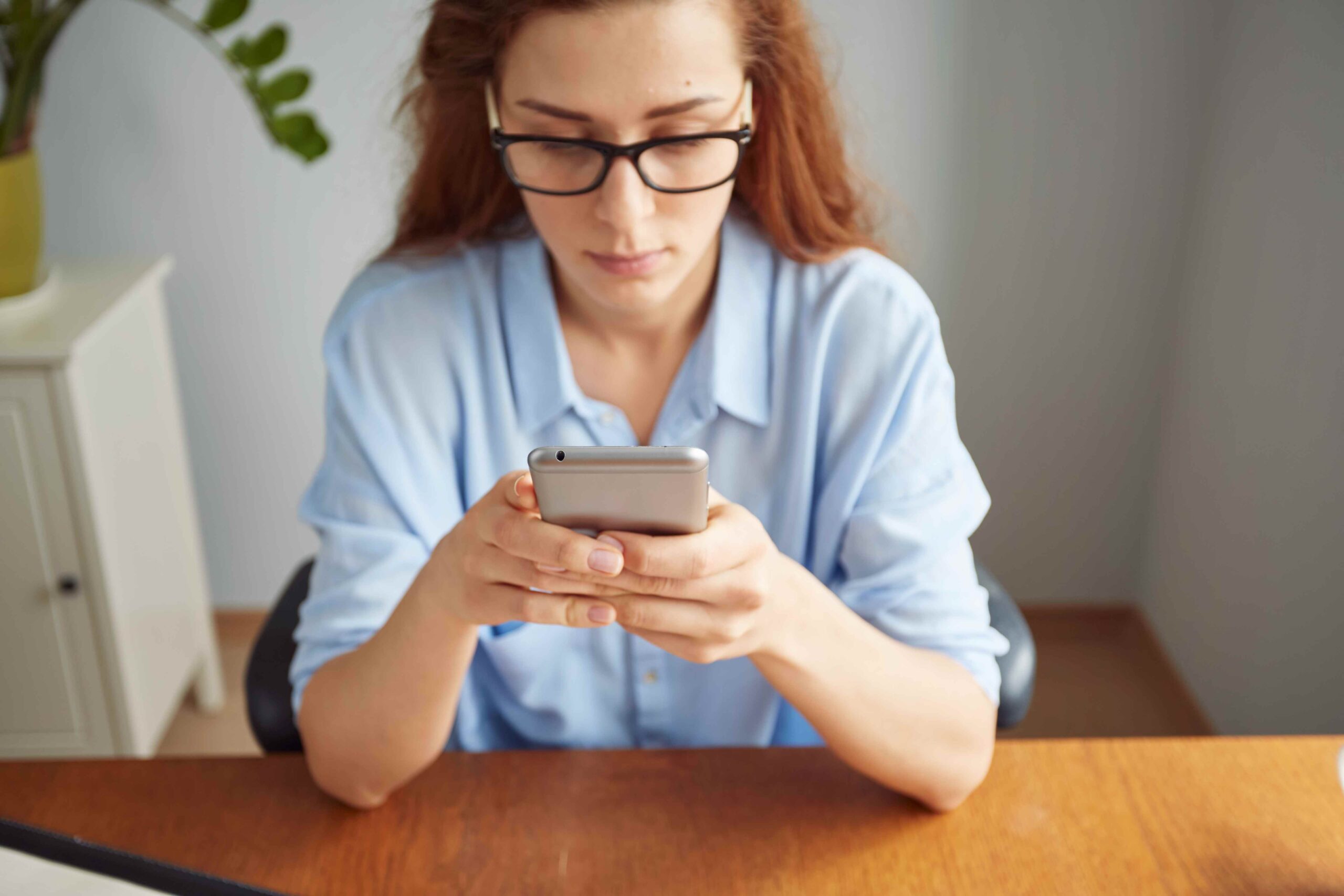 Cropped View Portrait Cute Redhead Girl Texting Cell Phone Wooden Desk 11zon Scaled